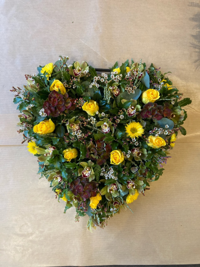 Wild at heart - Loose heart filled with seasonal flowers in a wild theme. 
Beautiful open heart. Flowers arranged on an oasis base. Seasonal flowers used to create a wild open look. Perfect for a tribute for that special person. 
Medium size shown in picture.