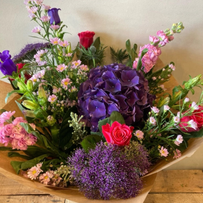 Summer vibes - A striking hand-tied bouquet featuring rich purple, vibrant pink and soft lilac tones for a bold and elegant display.