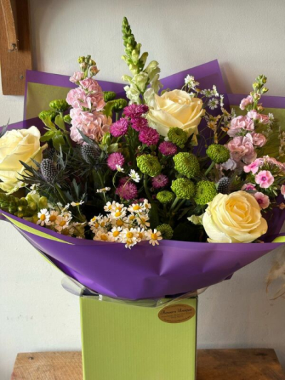 Spring Meadow - A vibrant hand-tied bouquet in soft cream, pink, purple and fresh green tones, beautifully arranged in a contemporary gift bag.